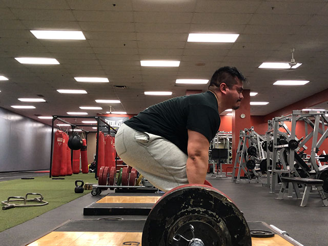 Alex power lifting in a large gym.