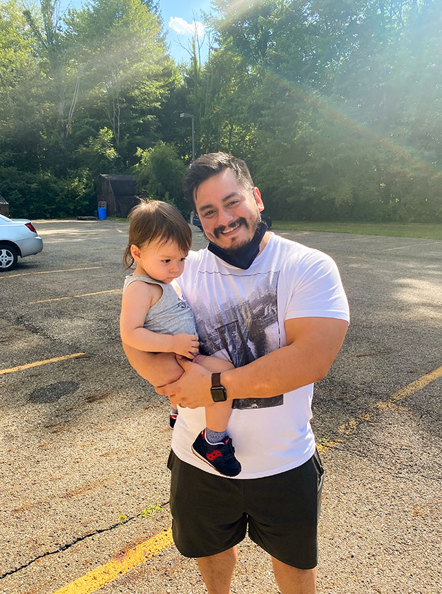 Alex holding his son on a sunny day.