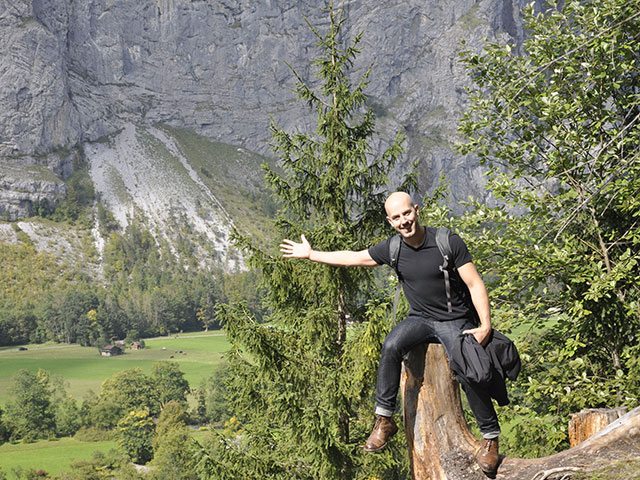 Donny posing on tree stump farmland and gigantic rock formation in background