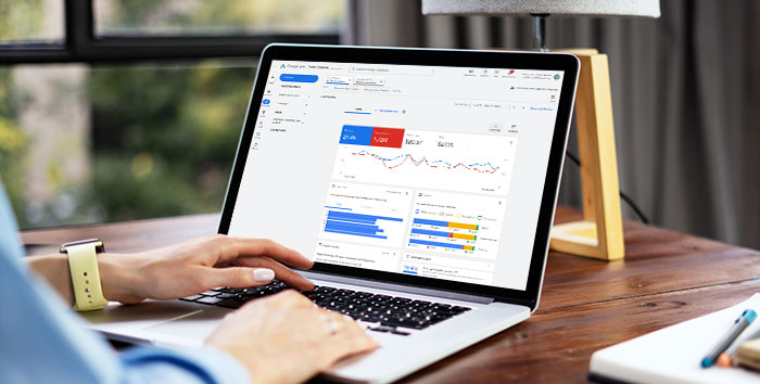 Person viewing website analytics dashboard with charts and performance metrics on a laptop at a wooden desk.