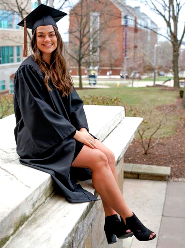 Kaitlyn in graduation gown on steps