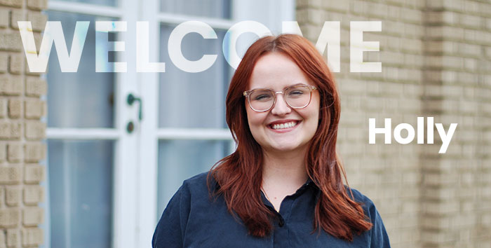 Holly Smith posing in front of a brick wall.